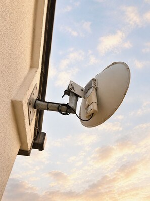 A satellite dish mounted on a building's exterior wall.