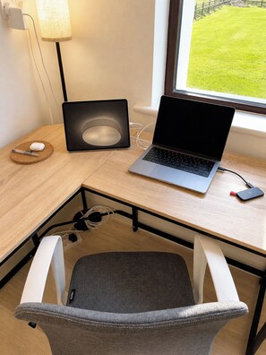 A corner desk with a laptop, a mouse, a lamp, and a chair.