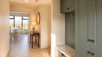 A hallway with a dining area, a table with chairs, a lamp, and a cabinet with drawers.