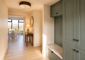 A hallway with a dining area, a table with chairs, a lamp, and a cabinet with drawers.