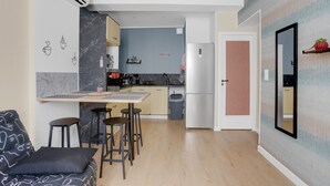 A modern kitchen with a marble backsplash, a dining area with stools, a refrigerator, and a wall-mounted shelf with a pineapple. - 'O'soleil' Apartment with Wi-Fi and Air Conditioning (Fréjus)