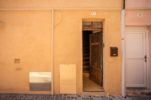 Une entrée d’immeuble avec une porte portant le numéro « 57 » et, à droite, une porte blanche portant le numéro « 59 ».