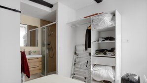 A hotel room with a bed, a wardrobe, a mirror, a bathroom with a sink, and a shower. - 'O'soleil' Apartment with Wi-Fi and Air Conditioning (Fréjus)