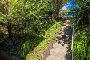 A concrete staircase surrounded by dense greenery and trees. - Hekerua Heights - premium holiday home with hot tub and ocean views, sleeps 6 (Waiheke Island)