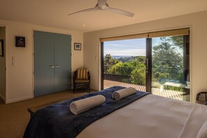 Een slaapkamer met een bed, een stoel, een kledingkast en een balkon met uitzicht.