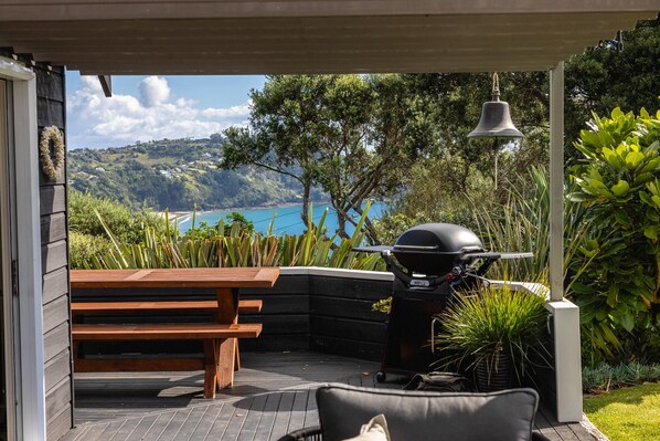 Outdoor dining - The Point - Onetangi. Luxury & Ocean Views - The Point is a private, light-filled home above Onetangi Beach with wide north-facing sea views. Surrounded by native bush, it offers a peaceful, secluded stay. Open-plan living includes a well-equipped ki (Waiheke Island)