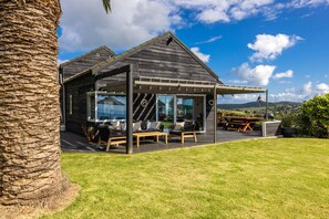 Outdoor dining - The Point - Onetangi. Luxury & Ocean Views - The Point is a private, light-filled home above Onetangi Beach with wide north-facing sea views. Surrounded by native bush, it offers a peaceful, secluded stay. Open-plan living includes a well-equipped ki (Waiheke Island)