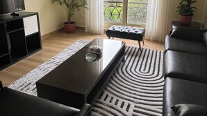 A living room with a sofa, a coffee table, a TV, and a potted plant. - Spacious 3-bedroom apartment in the heart of Sheikh Zayed with Garden view (Giza Governorate)