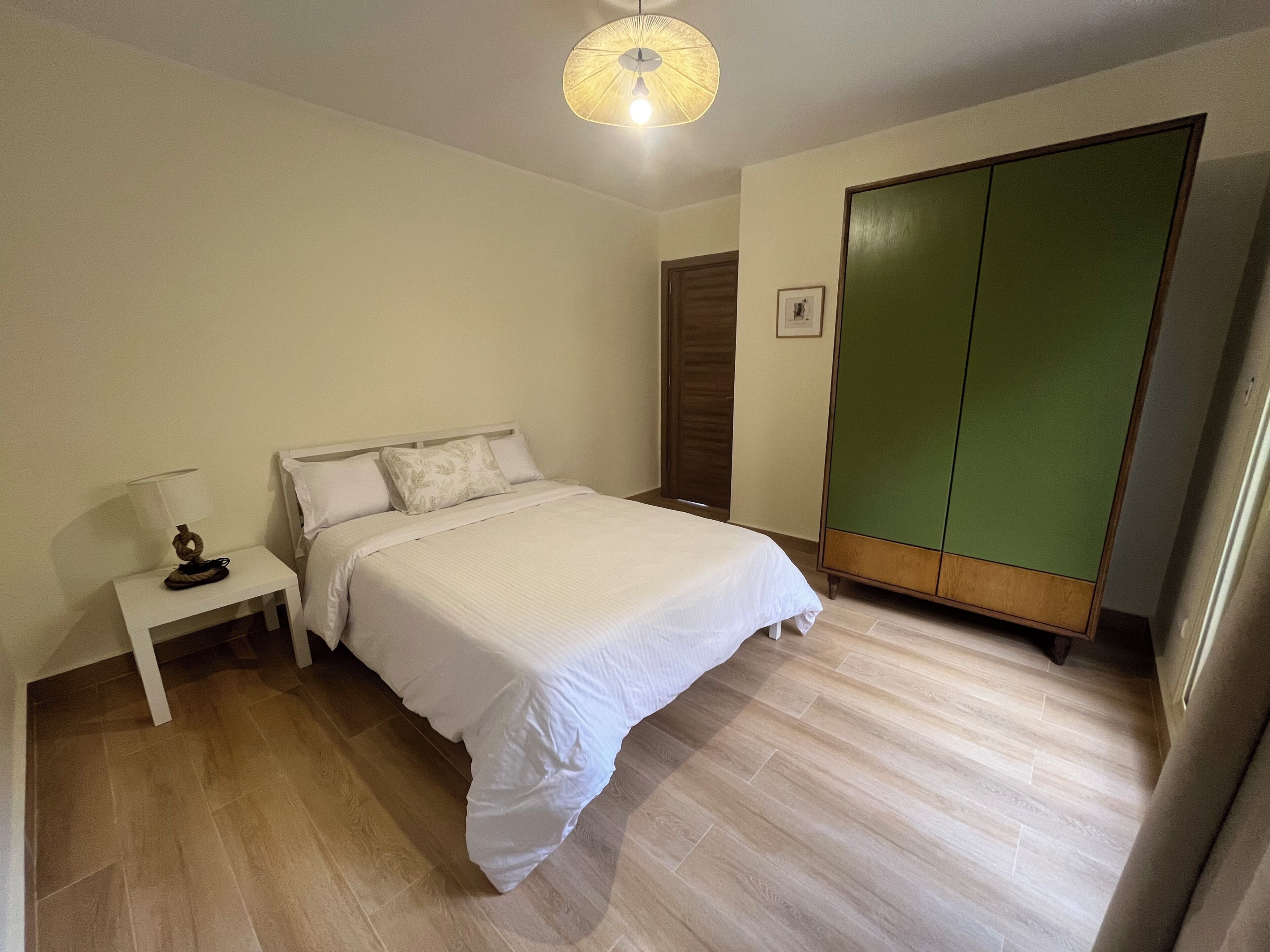 A bedroom with a bed, a nightstand, a wardrobe, and a ceiling fan.