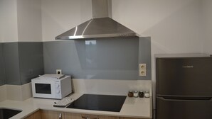 Una cocina con microondas, estufa y refrigerador.