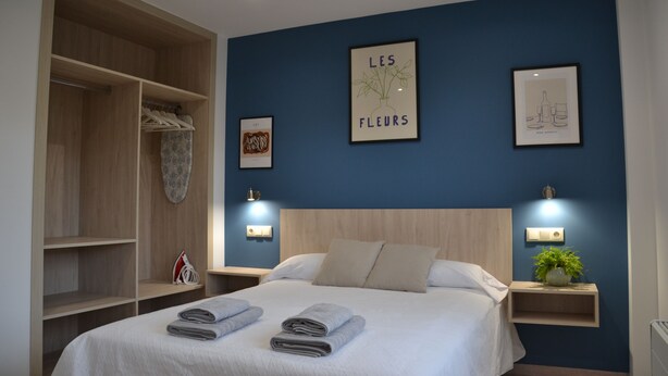 Un dormitorio con cama, armario y cuadros en la pared.