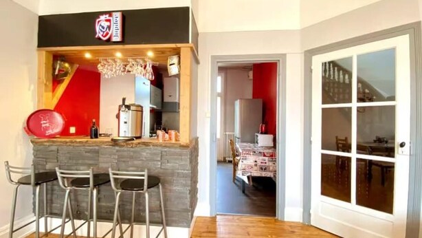Uma cozinha com bancada, piso de madeira e área de refeições com mesa e cadeiras.