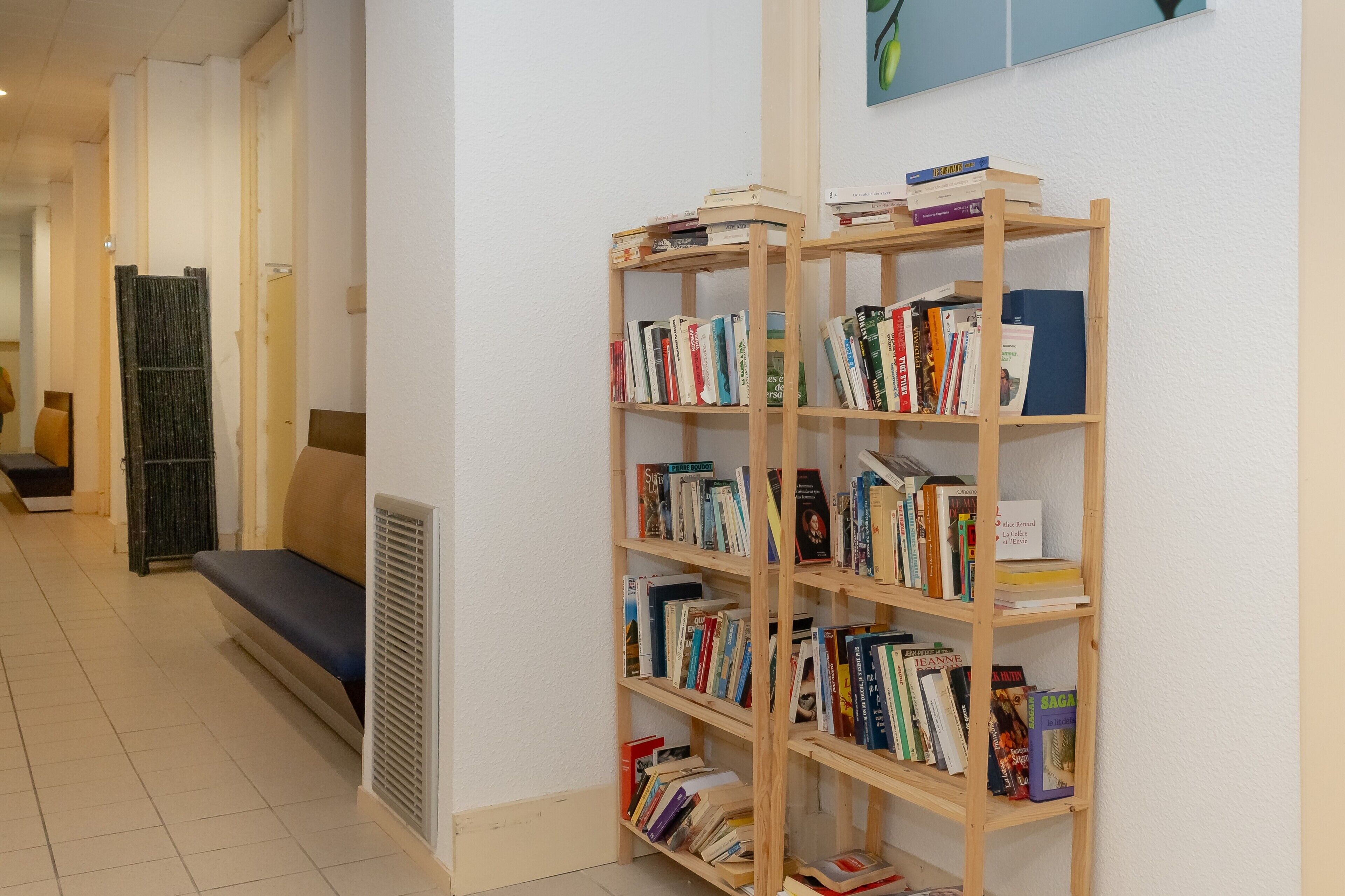 Een hal met een houten boekenkast vol boeken, een bankje en een aan de muur hangend schilderij.
