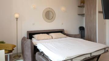 A modern bedroom with a bed, bedside table, floor lamp, and a mirror on the wall.