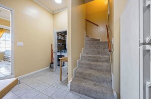 A hallway with a carpeted staircase, a door leading to a room with a bed, and a closet with shelves. - Master’s Magic Retreat-2 Bedrooms-Augusta Regional Airport-Feels Like Home (Augusta)