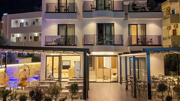 Un hotel de varios pisos con recepción, zona de estar al aire libre y piscina.