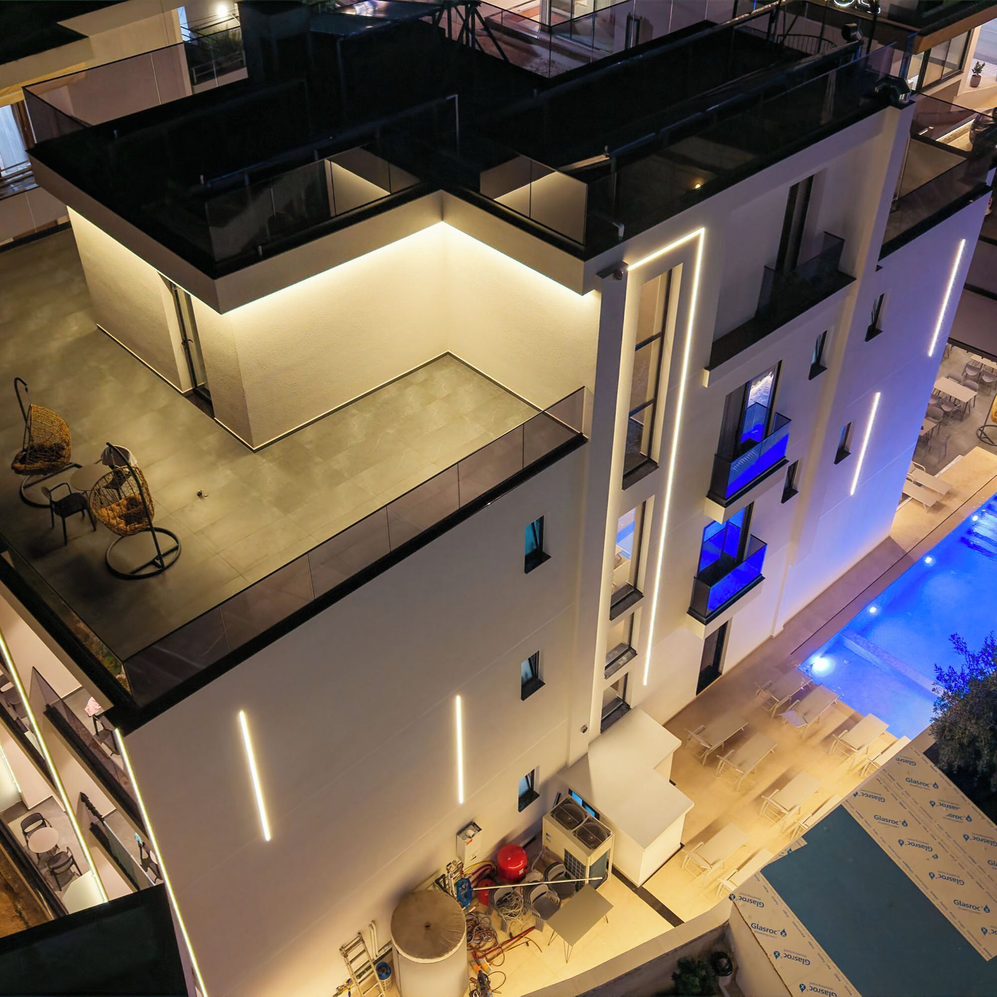 Un hotel de varios pisos con terraza en la azotea, piscina y diseño arquitectónico moderno.