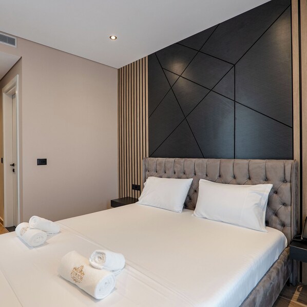 Une chambre d’hôtel moderne avec un grand lit, une tête de lit au motif géométrique et un panneau fixé au mur.