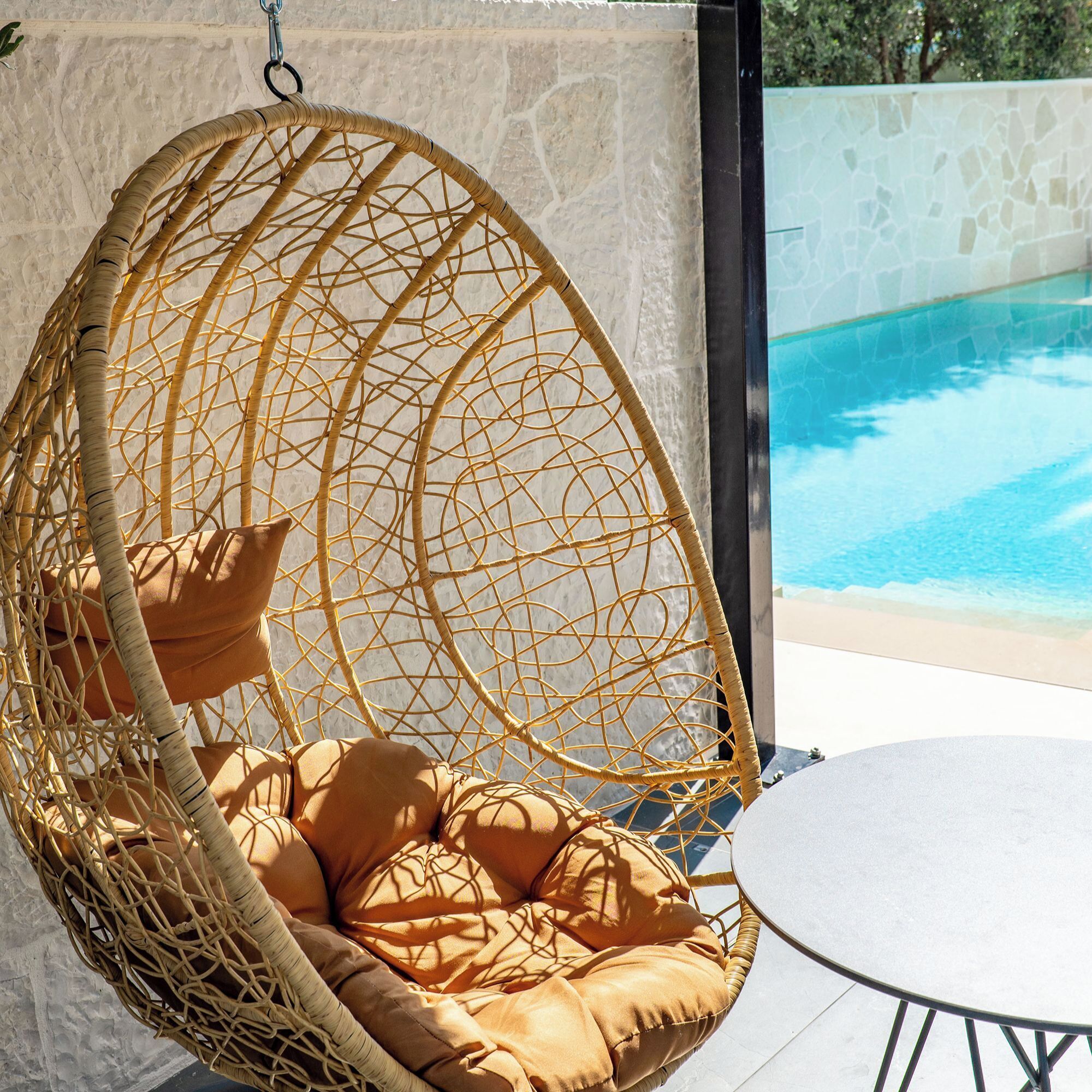 Ein Korbstuhl zum Aufhängen mit Kissen am Pool.
