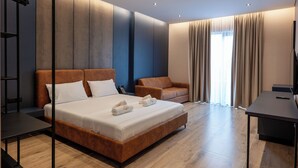 Una habitación de hotel moderna con una cama grande, un escritorio, un sofá y un televisor.