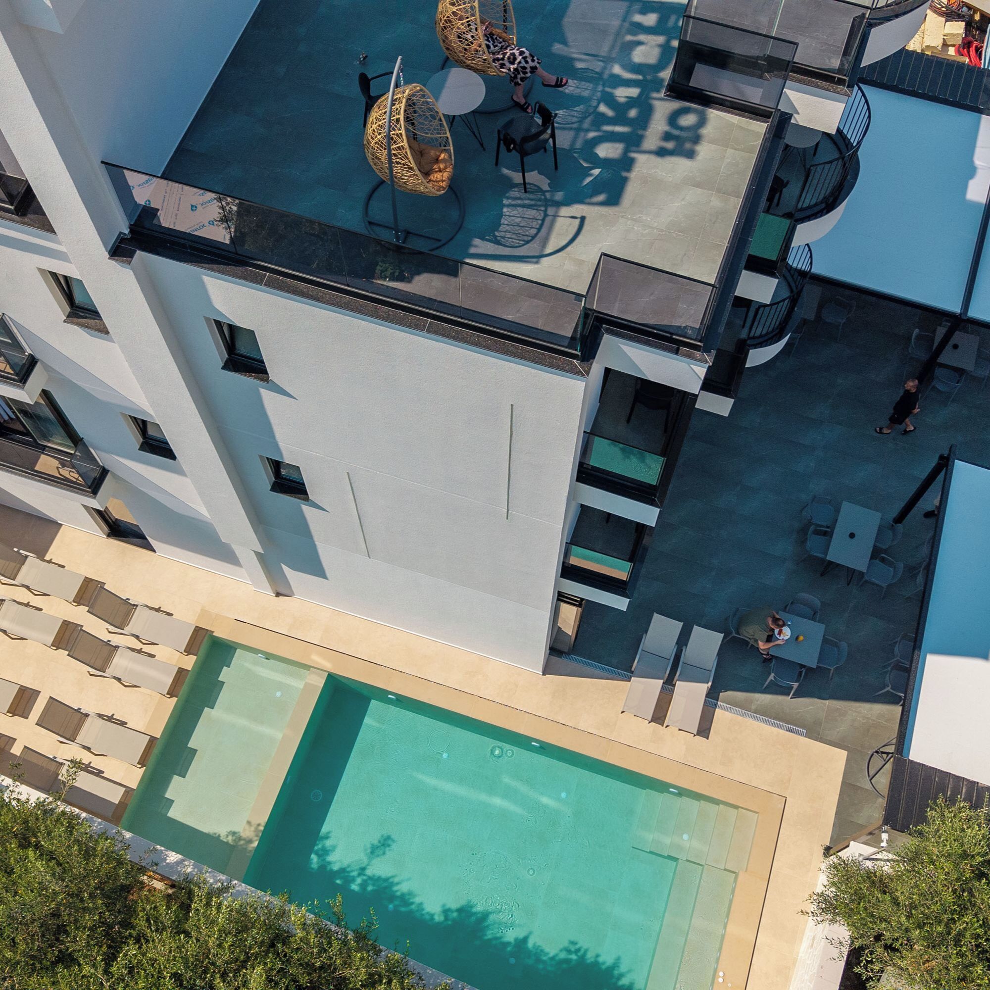 Vista aérea de um edifício moderno com piscina, área de estar ao ar livre e escada que leva a uma varanda.