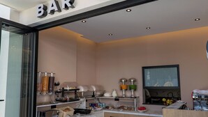 Un bar cafetería con mostrador de mármol, máquinas de café y un televisor.