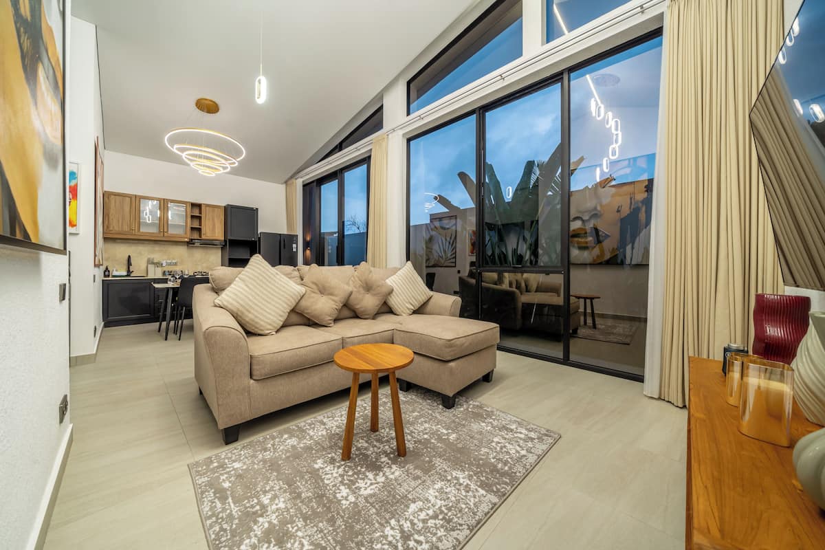 Una sala de estar moderna con un sofá, una mesa de centro y una cocina al fondo.