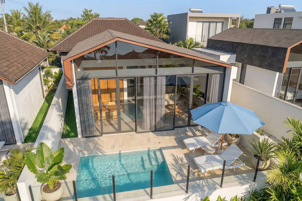 Una casa moderna con piscina, puertas de cristal y mobiliario de exterior.