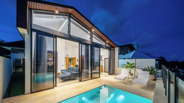 Een modern huis met een zwembad, grote glasramen en een terras.