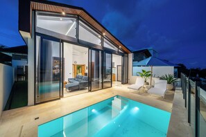 Una casa moderna con piscina, amplios ventanales y un área de patio.