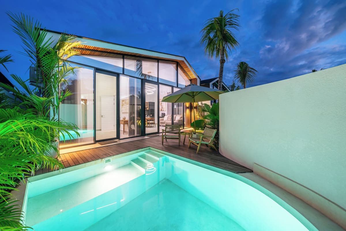 Una casa moderna con piscina, puertas de cristal y mobiliario exterior.