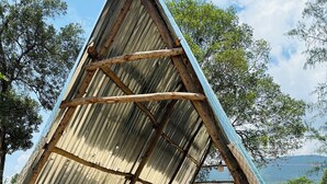 Estrutura metálica triangular com uma mesa e banquetas embaixo.