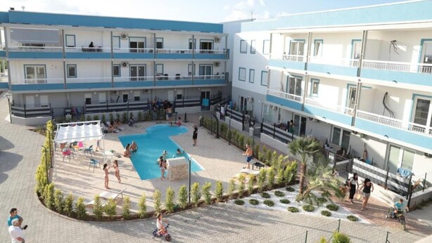Ein mehrstöckiges Hotel mit Innenhof, der einen Swimmingpool, Sitzgelegenheiten im Freien und einen angelegten Garten umfasst.