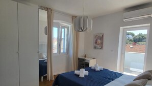 Ein Schlafzimmer mit Bett, Kleiderschrank, Schreibtisch, Stuhl und Fenster mit Blick.