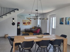 Un salon moderne comprenant un coin repas, un escalier et des œuvres d’art accrochées aux murs.