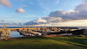 A marina with multiple boats docked, a grassy foreground, and a body of water in the background. - Beach Apartment in Amarilla Golf- Sleeps 4 (San Miguel de Abona)