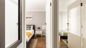A bedroom with a bed, bedside table, lamp, and a painting on the wall. - Rosario’s Village | 2-Bed Unit 09, Bryanston (Bryanston)
