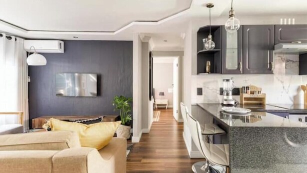 A modern kitchen with a marble countertop, a built-in oven, and a hanging light fixture. - Rosario’s Village | 2-Bed Unit 09, Bryanston (Bryanston)