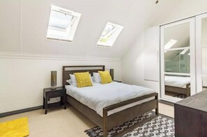 Ein Schlafzimmer mit Bett, Nachttisch, Lampe und Spiegel.