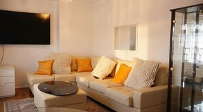 A modern living room with a sofa, coffee table, and a flat-screen TV. - Cosy Central Flat| Perfect for work, families and couples (Northampton)