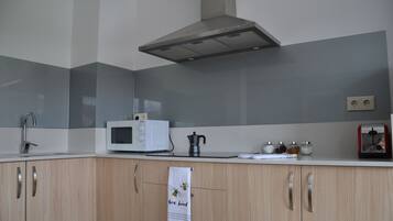 Una cocina moderna con microondas, tetera y armarios.