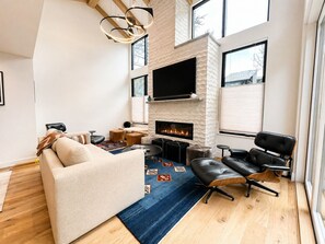 Ein modernes Wohnzimmer mit Kamin, Ledermöbeln und einem großen Fernseher.