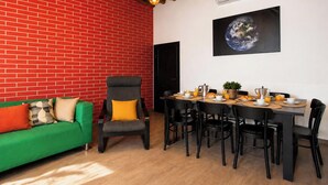A room with a red brick wall, a green sofa, a dining table with chairs, and a globe artwork on the wall. - Entire House Florence: 3 Bedrooms, 2 Bathrooms, and Free Parking by TuscanyWeGo (Firenze)