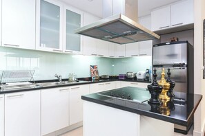 A modern kitchen with white cabinets, a stainless steel refrigerator, a gas stove, and a glass backsplash. - 1 Bed Serviced Skyvilla with view (Krung Thep Maha Nakhon)