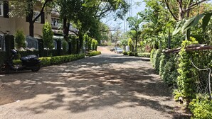 A paved road flanked by greenery, a parked scooter, and a distant car. - Serenity the villa by Beta Bawarchi (Pachmarhi)