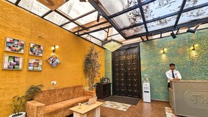 A reception area with a sofa, coffee table, and a receptionist desk. - Serenity the villa by Beta Bawarchi (Pachmarhi)
