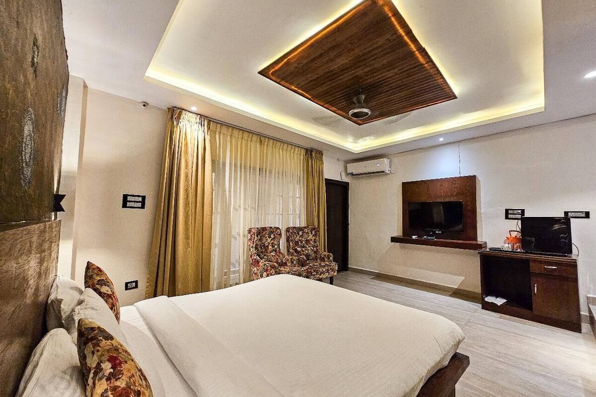 Una habitación de hotel con una cama grande, televisión, escritorio y lámpara de techo.