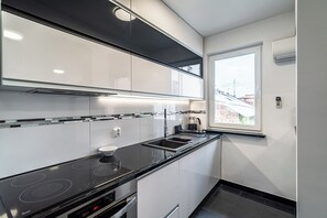 Eine moderne Küche mit schwarzem Arbeitsplatz, Edelstahlgeräten und einem Fenster mit Blick auf Gebäude.
