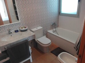 Une salle de bain équipée d’un lavabo, de toilettes, d’une baignoire et d’un bidet.