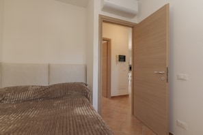 Ein Schlafzimmer mit einem Bett, einer Holztür und einem Flur, der zu einem Badezimmer führt.
